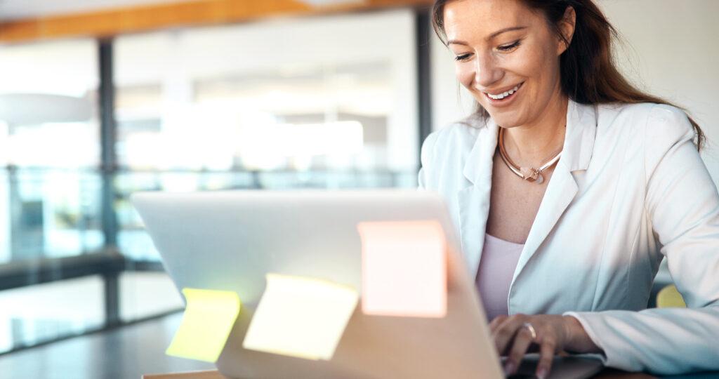 Smiling woman at a laptop creating an email marketing strategy