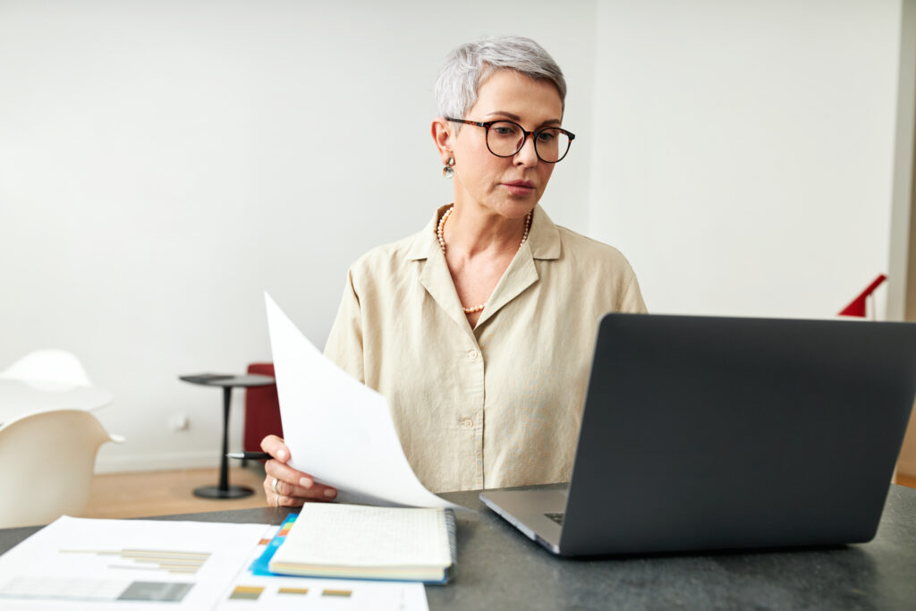 mature woman with documents using laptop at desk i 2023 09 06 01 15 13 utc