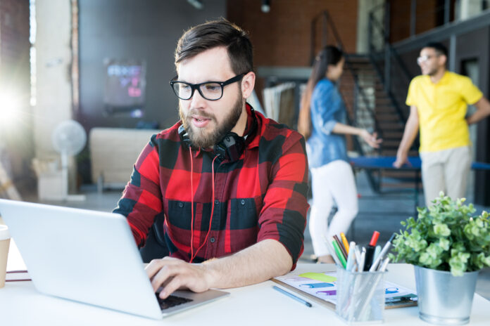 Bearded man creating AI images for church graphics on a laptop