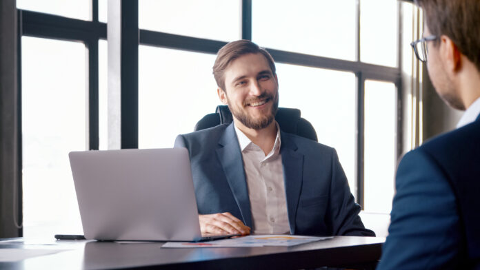 Youngman in a suit talks to a man in the workplace